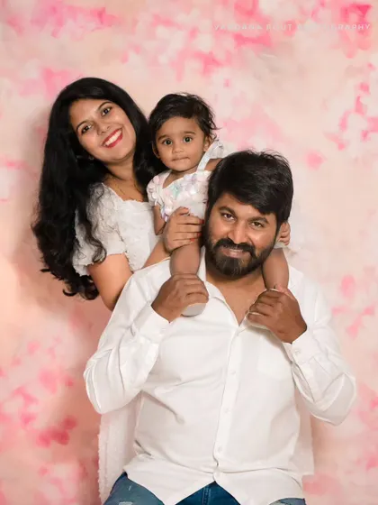 A fun family portrait with the daughter sitting on her father's shoulders. This playful pose adds a touch of fun and personality to their studio photoshoot.