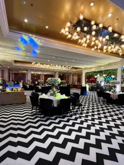 An indoor engagement party with a bold and modern aesthetic. The striking black and white chevron floor contrasts beautifully with the elegant table settings and grand lighting fixtures, showing how I transform indoor venues.