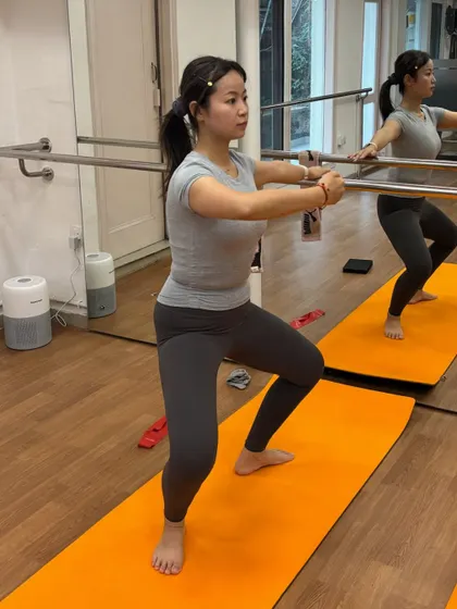 A member focuses on her form during a squat at the barre, a key movement for building leg and glute strength.