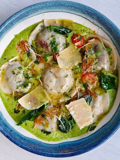 A bowl of my vibrant green ravioli, filled with deliciousness and topped with parmesan shavings. It's mischief and mouthfuls, all in one.