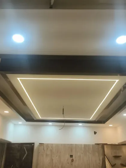 A different living room ceiling design featuring a mix of dark wood beams and white panels, with a square of profile lighting in the center.
