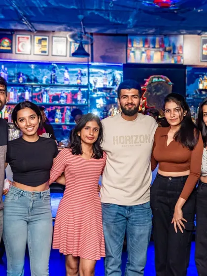 A large group of friends posing in front of the bar, ready for a memorable night.