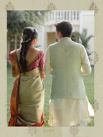 A back view of the couple, showcasing the bride's magenta blouse with its intricate back embroidery and elegant design.
