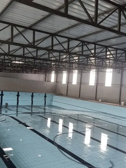 The structural design of our indoor pool facility, showing the steel truss roof and ample natural light from the high windows.