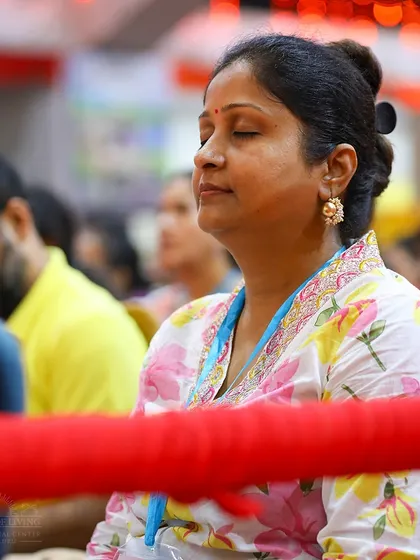 A woman sits in quiet contemplation during a Navratri puja. Our programs provide a space for you to disconnect from daily worries and reconnect with your inner self.