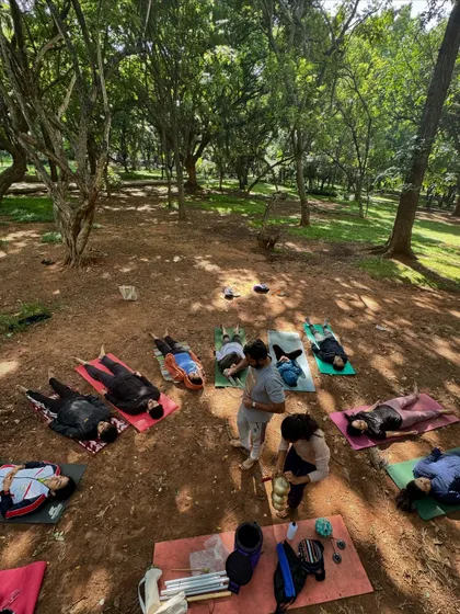 An overhead view of a magical Yoga Day celebration at Cubbon Park. Participants lie on their mats, immersed in the sounds of nature and healing instruments. These outdoor sound baths offer a unique way to connect with the earth and find inner peace.