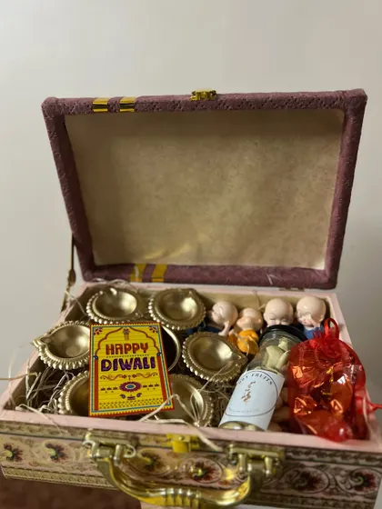 The full view of the ornate pink and gold Diwali box, filled with traditional gifts.