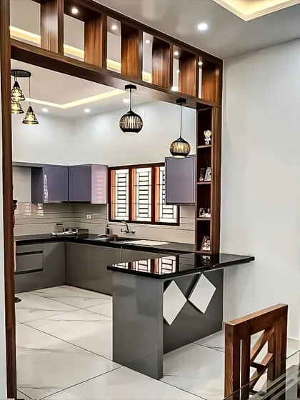 This design features a beautiful wooden archway that frames the open kitchen, with a peninsula breakfast bar that connects it to the dining space. The grey cabinets and glossy black countertop offer a modern contrast to the warm wood elements.