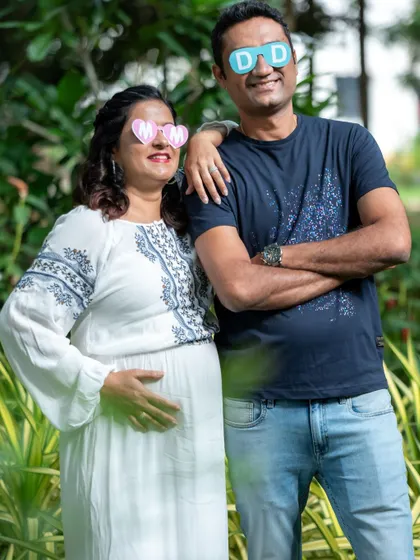 A playful couple portrait with fun "MOM" and "DAD" glasses. This casual outdoor shot shows their fun-loving personalities.