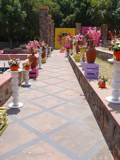 The pathway to the event was lined with an array of colorful flowers in terracotta pots and on painted crates, creating a cheerful and welcoming walkway for guests by the pool.
