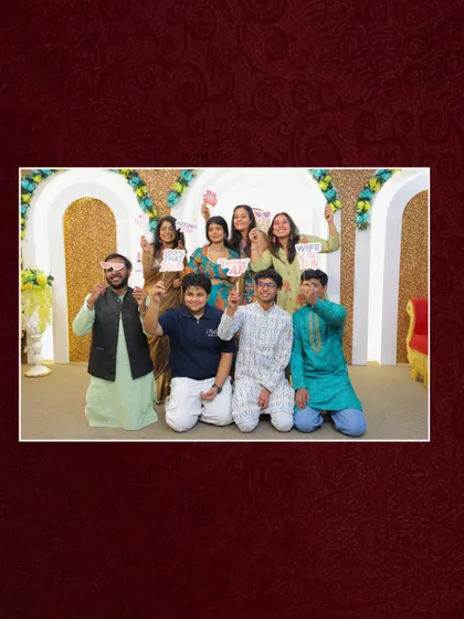 A happy group photo with guests holding fun props at the mehndi. My goal is to create an environment where everyone lets loose and creates joyful memories together.