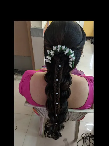 A fishtail braid with pearl accents, adorned with a unique arrangement of white flowers.