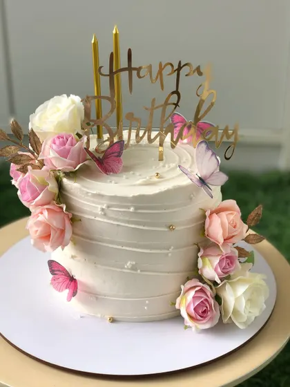 A lovely white cake adorned with pink and white roses and edible butterflies.