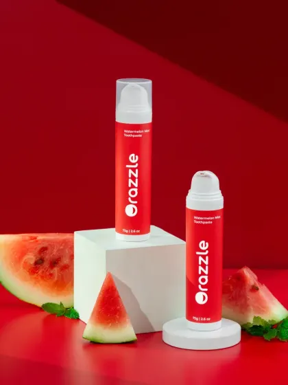 This composition for Orazzle's watermelon toothpaste uses white pedestals and fresh fruit to create a clean and appealing product display. The varying heights add visual interest to the shot.