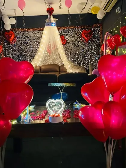 A dreamy, romantic decor setup with a canopy, fairy lights, and dozens of red heart-shaped balloons. It's the perfect way to surprise your loved one.