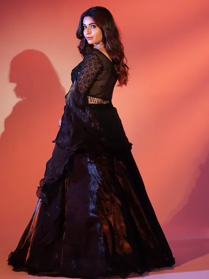 A back view of the black lehenga, showing off its dramatic silhouette against a warm, glowing background. It's pure elegance.