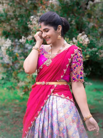 A smiling portrait in the pink and silver-grey half saree, showing the intricate embroidery on the blouse.