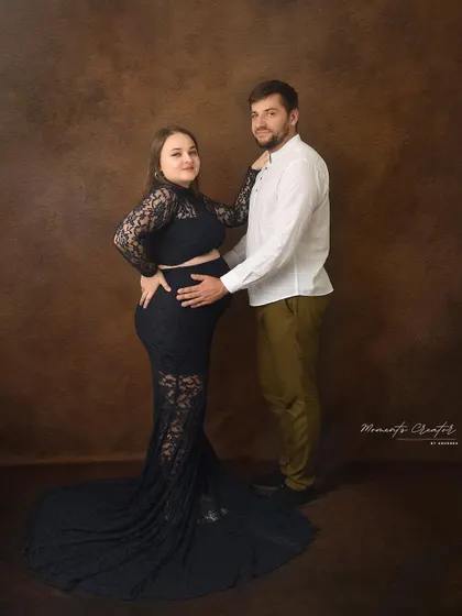 A beautiful portrait showcasing the baby bump. The partner's hands gently cradle the bump, a classic pose that emphasizes their shared journey.