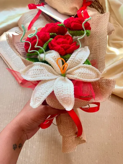A hand holding the red rose and white lily bouquet, showing off the paw print tattoo that is a tribute to my original inspiration, Buddy.