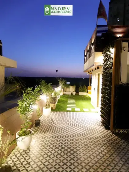The tiled patio area of the Gwal Pahari terrace, with subtle lighting along the boundary wall.