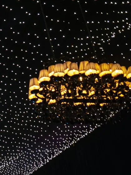 The unique silhouette of the lampshade chandelier against the twinkling fairy light ceiling.