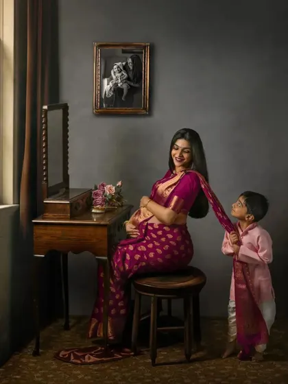 A duplicate of ID 7, this heartwarming studio scene shows a young boy playfully tugging on his mother's saree. This portrait tells a story of family bonds and anticipation, using vintage furniture to frame the moment.