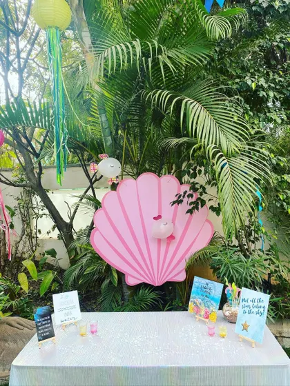 The main activity and snack table, beautifully decorated with a giant pink seashell, ocean-themed signs, and hanging jellyfish, creating an inviting focal point for the party.