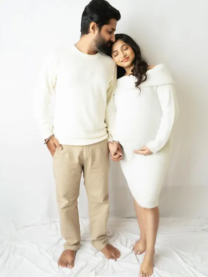 A tender moment between expecting parents, coordinated in soft white outfits. This minimalist setup keeps the focus purely on your emotion and connection.