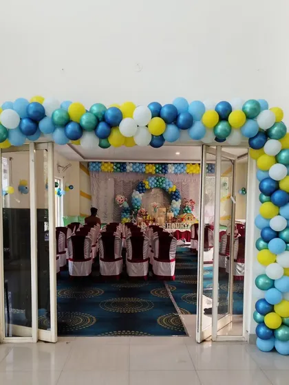A duplicate image showing the same colorful L-shaped balloon arch at the entrance of a hall, providing a clear view of the event space inside.