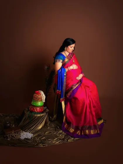 A traditional maternity shoot with cultural elements. The rich colors of the saree and the props create a regal and timeless portrait.