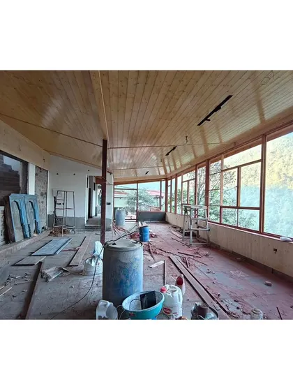 Another shot during the construction phase, showing the raw structure and the careful assembly of the wooden ceiling and window frames against the backdrop of the stunning Uttarakhand landscape.