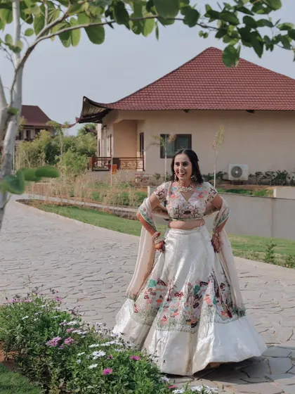 A full-length portrait of the bride in a beautifully embroidered lehenga, posing confidently in a resort garden.