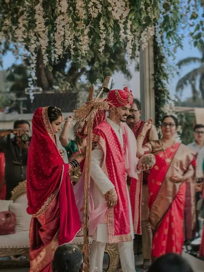 A candid shot from the pheras. The couple circles the sacred fire, their colorful traditional attire vibrant under the daytime sky, surrounded by their loved ones.