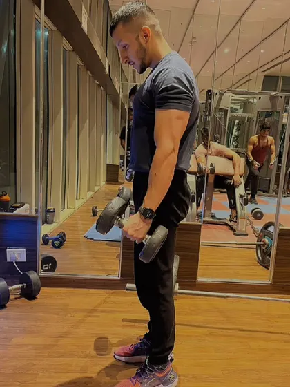 A side view of a dumbbell hammer curl. This variation helps target both the bicep and the brachialis muscle, leading to fuller-looking arms.