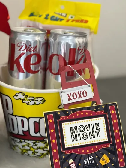 A close-up of our Netflix and Chill hamper, perfect for a cozy movie night. It includes a popcorn bucket, Diet Coke, and a movie night-themed card.