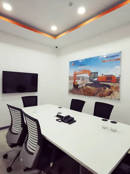 A secondary meeting room with clean white walls and corporate branding. This functional space is designed for smaller team meetings and client discussions.