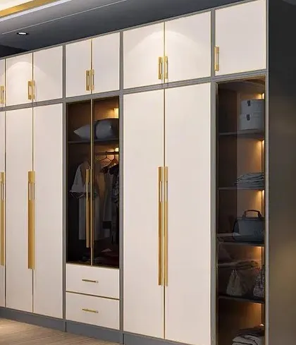A modern floor-to-ceiling wardrobe in white with elegant gold handles. This design includes a glass-paneled section for displaying accessories, combining open and closed storage beautifully.