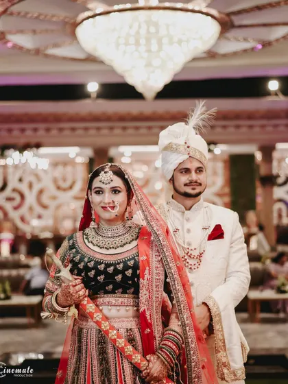 A regal portrait of the bride and groom, with the bride holding a traditional sword, showcasing cultural elements of the wedding.