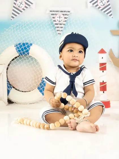 Holding onto his nautical rope, this baby boy looks like a seasoned captain in his sailor-themed photoshoot.