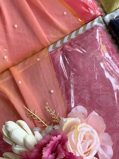 Trousseau packaging for sarees, with each piece carefully wrapped and adorned with a floral touch. The pearl details on the fabric add an extra layer of elegance.
