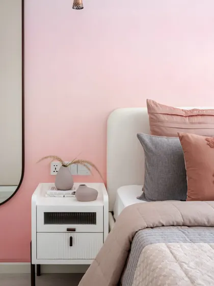 A close-up of the pink ombré wall and minimalist white nightstand, showcasing the gentle transition of color that creates a captivating backdrop.