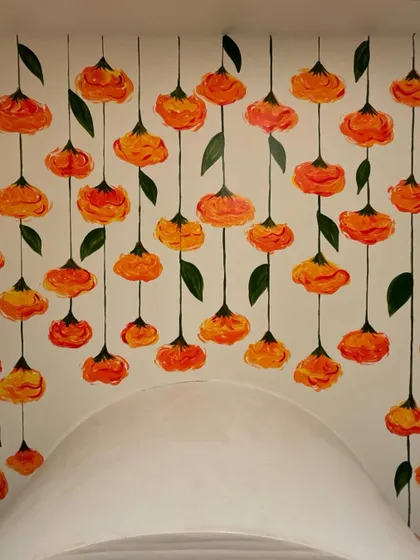 A close-up of the marigold mural within the arched pooja nook. The way the flowers cascade down the sides adds depth and dimension.