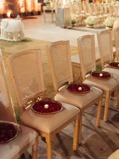 Elegant guest seating for the wedding ceremony, with each chair adorned with a plate of fresh rose petals and a small candle, inviting guests to be part of the celebration.