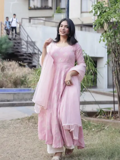 A full-length shot of a woman in a flowing pink Anarkali, captured mid-stride. This image showcases the entire outfit and its graceful movement.