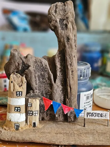 Another piece from our in-progress driftwood collection. This one features a little "Paradise" sign and a festive banner, showing how we build stories into our miniature sculptures.