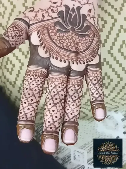 A close-up of a lotus-centric design on the palm. The fingers feature a delicate criss-cross pattern, which is a beautiful and popular filler element.
