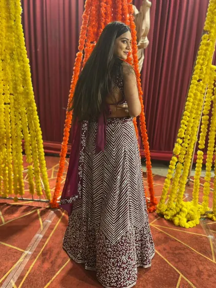 A back view of the client in the maroon chevron lehenga, highlighting the backless design of the blouse.