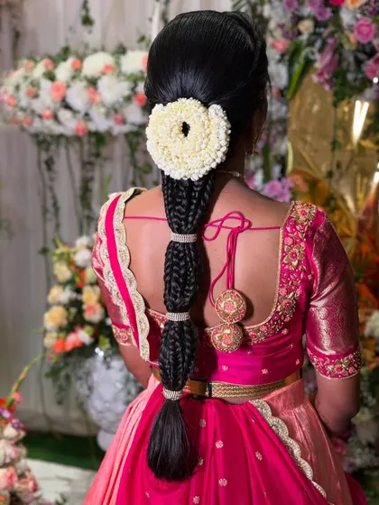 A closer view of the segmented braid, highlighting the neatness of the sections and the beauty of the fresh jasmine flower arrangement. The hanging tassels add a playful, traditional element.