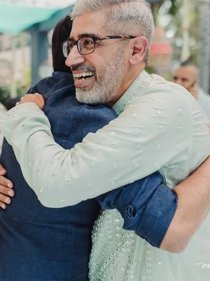 A happy moment between a father and a friend at a wedding, sharing a warm hug. Weddings are about celebrating with all your loved ones.