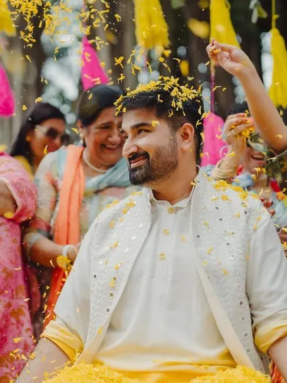 The groom is showered with flower petals by his family, a moment of pure joy and blessing during the Haldi ceremony.